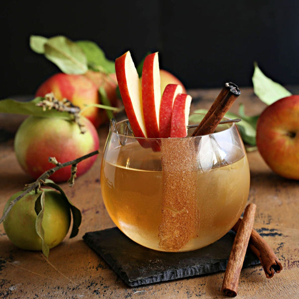 A Spiced Apple Old Fashioned with bourbon, apple cider, and Rustic Oak Spiced Apple Mixer, served with a cinnamon sugar rim and apple slice garnish.