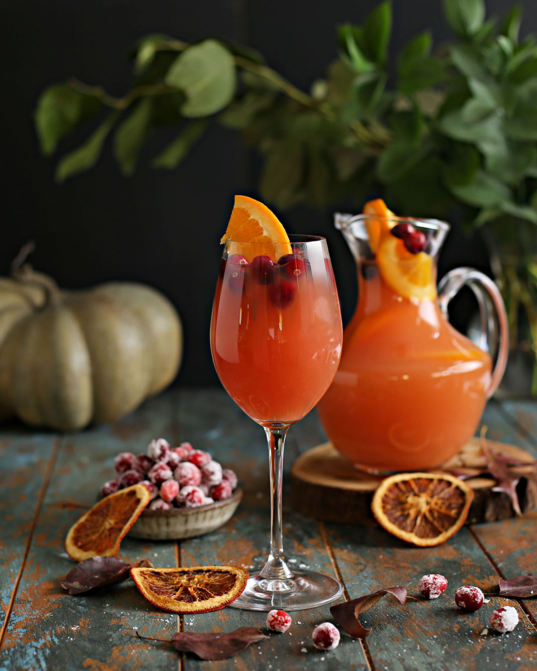 A pitcher of Autumn Sangria with whiskey, cranberry juice, orange juice, white wine, and Rustic Oak Orange Barrel Aged Mixer, garnished with citrus slices.