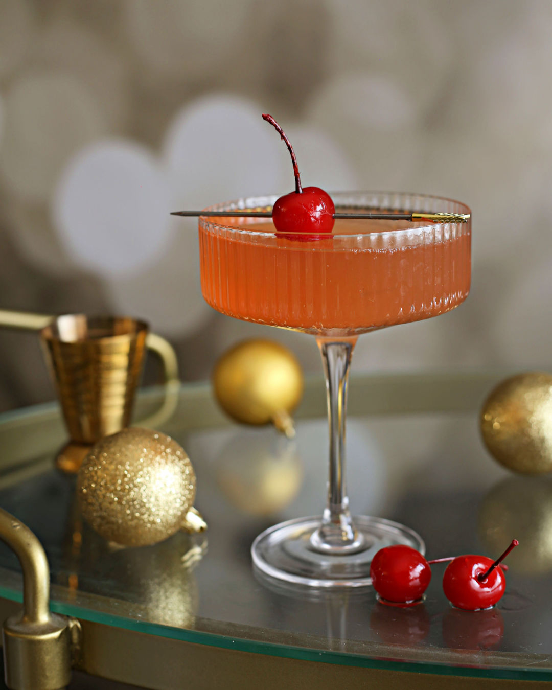 A Cherry French 75 cocktail with gin, lemon, Rustic Oak Sour Cherry Mixer, and champagne, garnished with Luxardo cherries in a flute glass.
