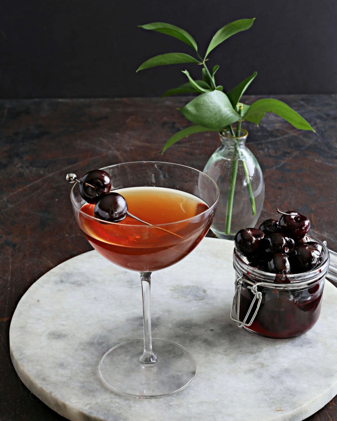 A rich Cherry Manhattan cocktail with bourbon, sweet vermouth, and Rustic Oak Sour Cherry Mixer, garnished with Luxardo-style cherries.