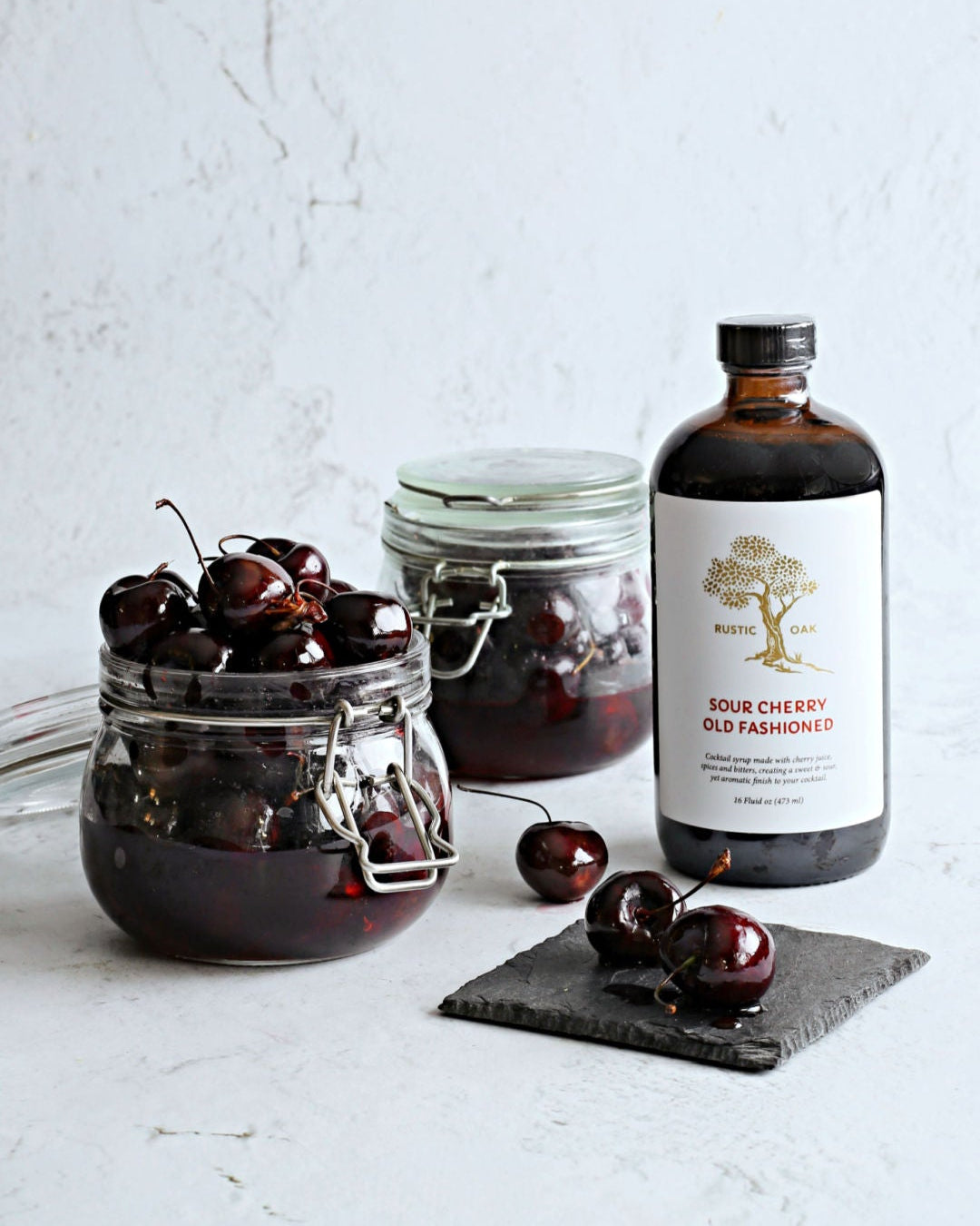 Homemade Luxardo-style cocktail cherries in a jar made with Rustic Oak Sour Cherry Mixer, Maraschino liqueur, and warm spices.