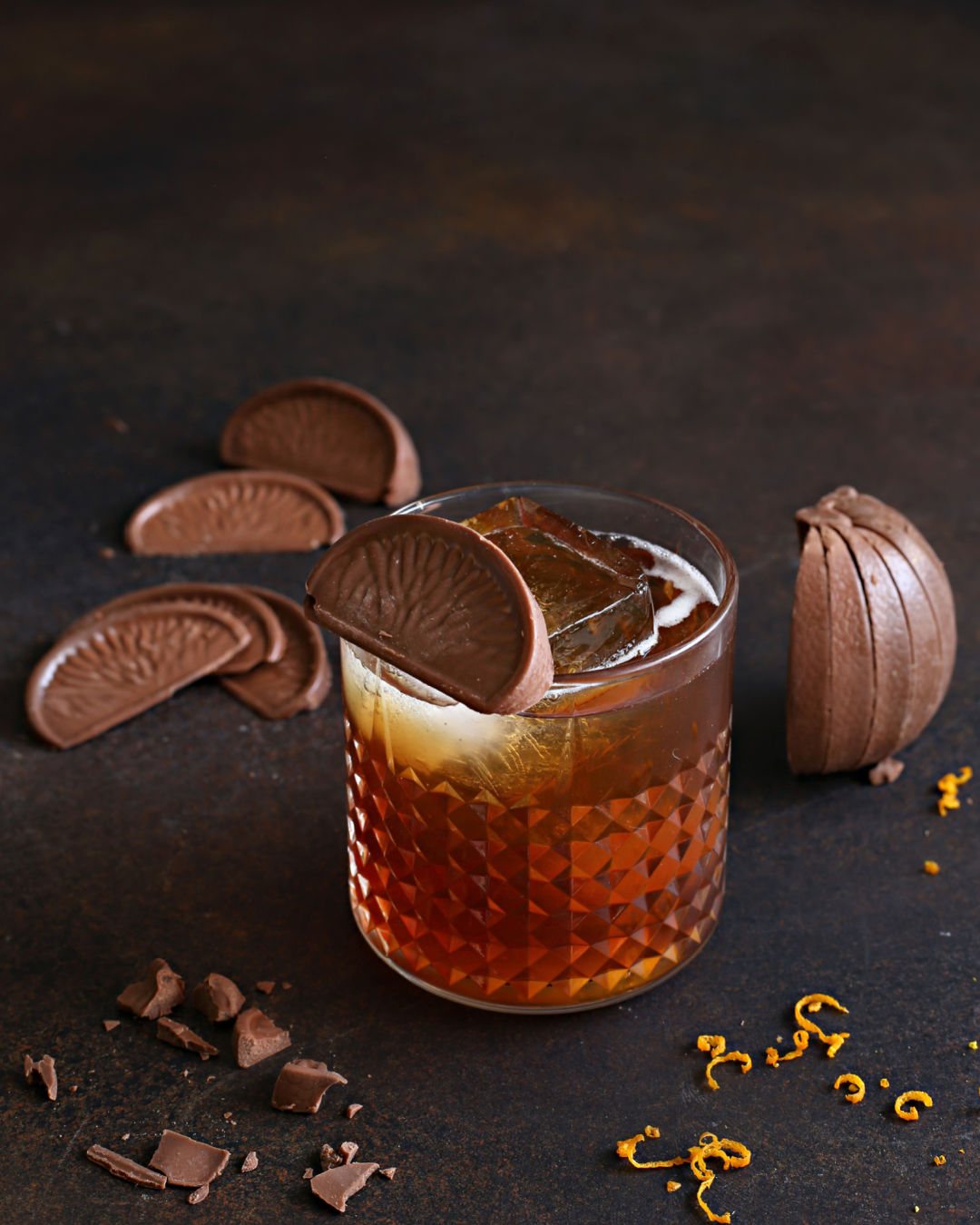 A Chocolate Orange Manhattan with bourbon, sweet vermouth, coffee liqueur, Rustic Oak Orange Mixer, and mocha bitters, garnished with an orange peel.