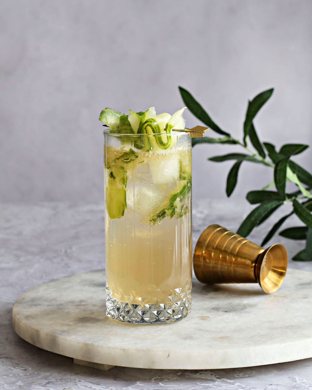 A zero-proof Cucumber Highball with Rustic Oak Traditional Mixer, orange bitters, and tonic water, garnished with cucumber slices.