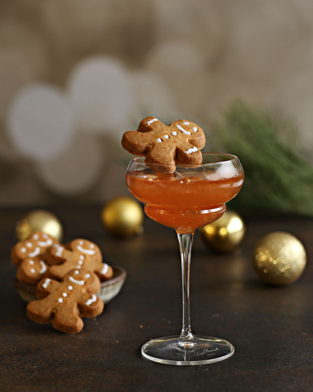 A Gingerbread Whiskey Sour with whiskey, fresh ginger, lemon, gingerbread syrup, and Rustic Oak Barrel Aged Mixer, garnished with a gingerbread cookie.