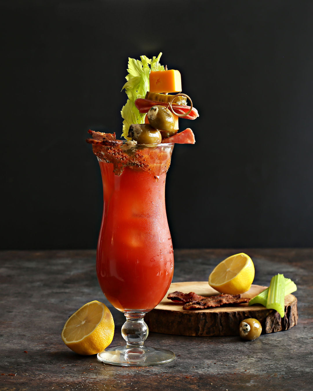 Loaded Bloody Mary garnished with bacon, blue cheese stuffed olives, salami, pickles, and cheddar cheese