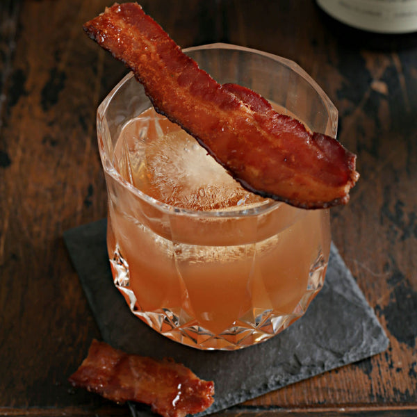 Maple Leaf Cocktail in a rocks glass garnished with maple glazed bacon