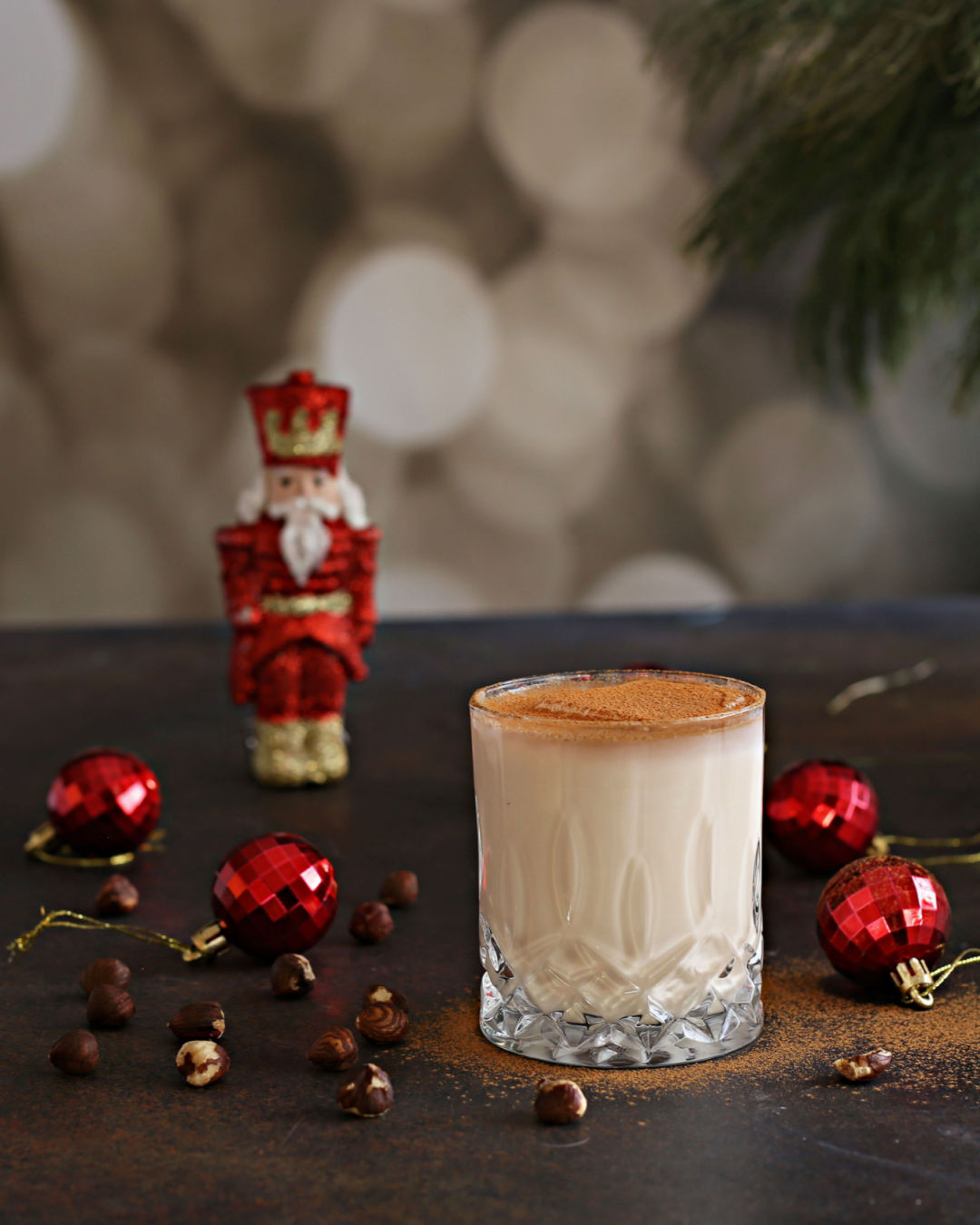 A creamy Nutcracker holiday cocktail with vodka, hazelnut liqueur, half and half, Rustic Oak Traditional Mixer, and cinnamon, served in a festive glass.