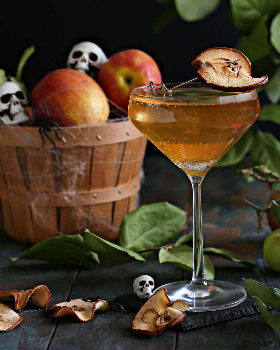 The Haunted Orchard Halloween cocktail with vodka, apple cider, Rustic Oak Traditional Mixer, and prosecco, garnished with an apple chip for a spooky presentation.